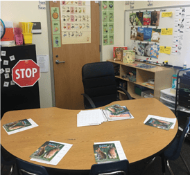 Four sets of student texts and materials laid out at a half circle table with texts and resources for the teacher at the center. 