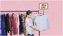 A girl standing next to a clothing rack with a 30 percent off sign on it. The girl is holding a white shirt.