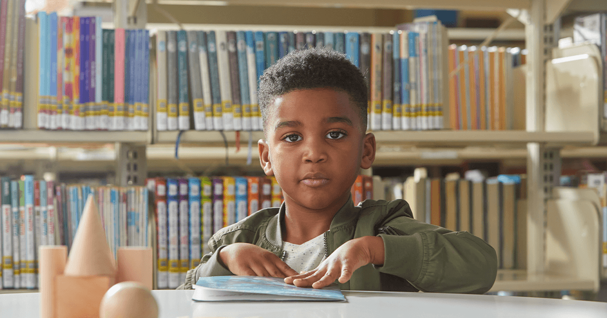 Young boy in library with a book.