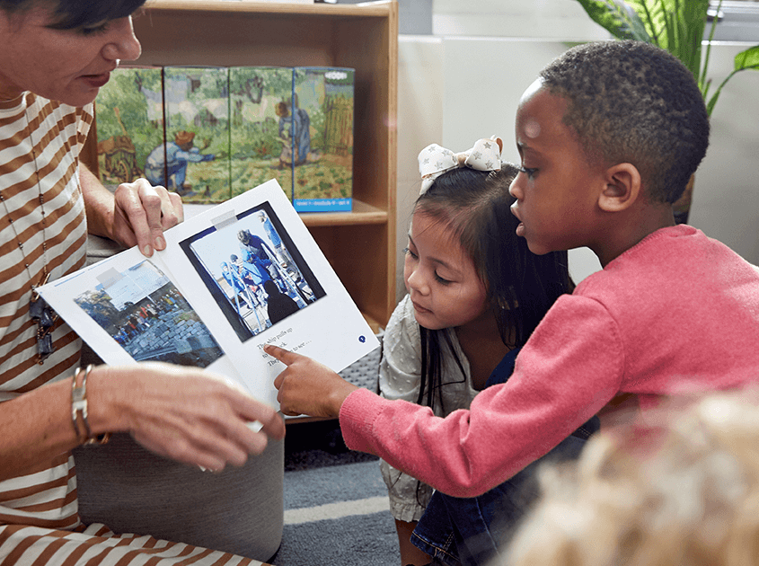 Two children, a boy and a girl, are looking closely at a book.