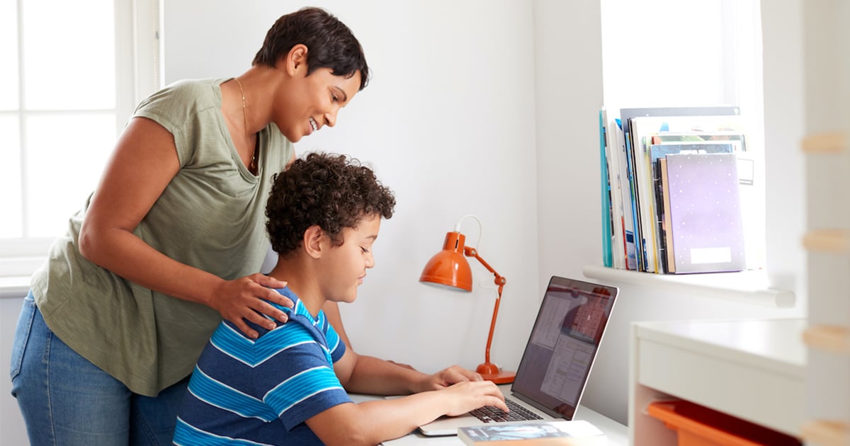 Imagen de un estudiante usando una computadora portátil, junto a un familiar.