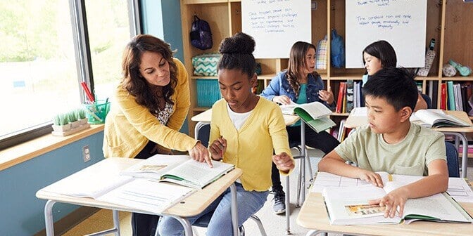 Arts and Letters teacher helping young student at desk