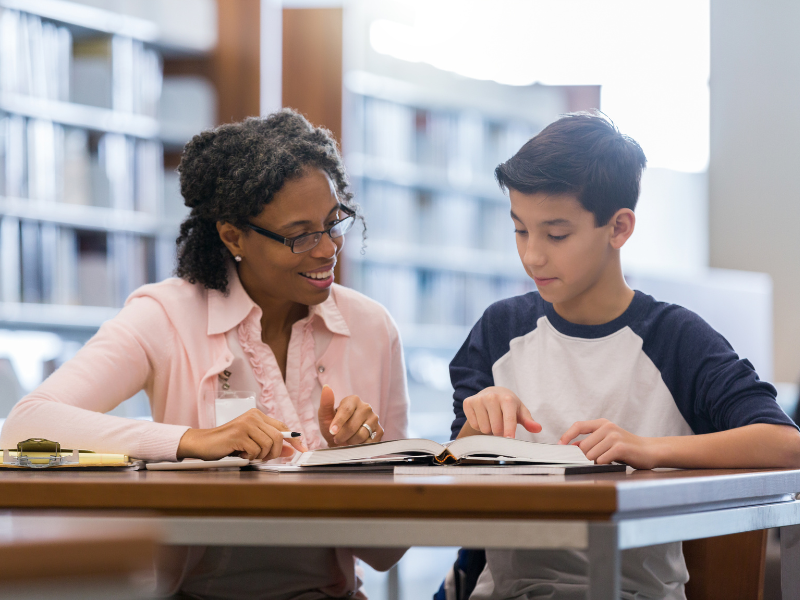 Educator and student looking at book together