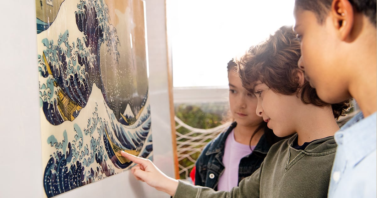 Three students looking at the painting of The Great Wave