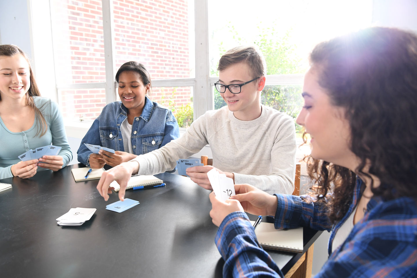 High School students play a math card game at a table.