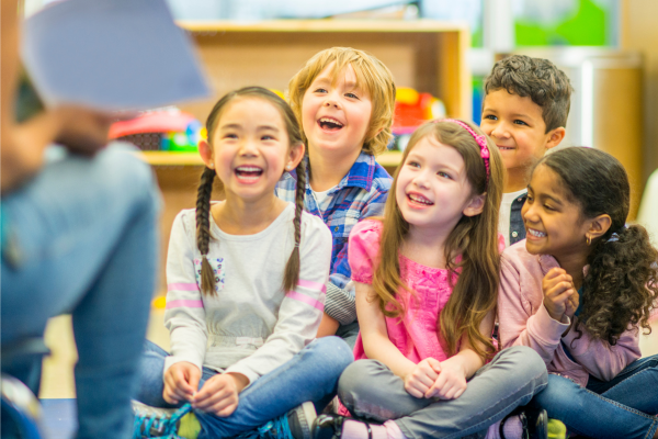 Educator reading to a group of smiling students